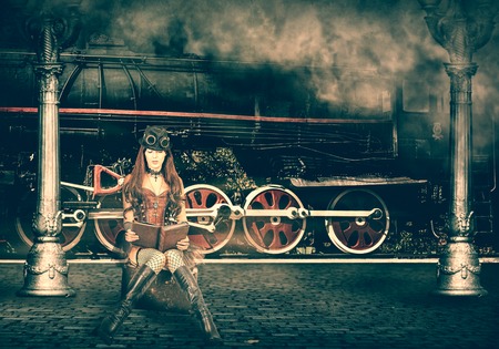 Steampunk and retro-futurism style. Woman traveler sitting on suitcase on platform of Railway Station. Near old train and clouds of smokeの写真素材