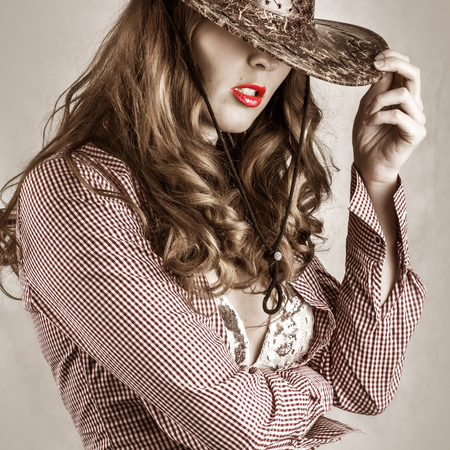 Beautiful cowgirl style woman wearing cowboy hat, studio shotの写真素材
