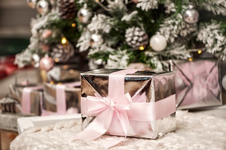 Macro view of present christmas box with tender pink ribbon. gift under the eve treeの写真素材