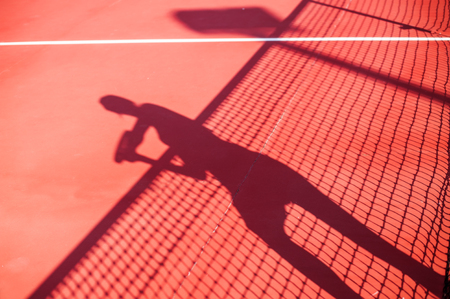 Tennis competition concept shadow of Woman holding racket playing tennis and waiting for the service while standing on court during matchの写真素材
