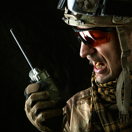 close up portrait of handsome military man. Macro shot on black background with portable radio transceiverの写真素材