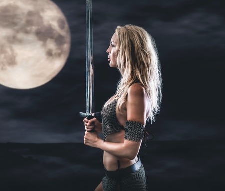 beautiful sexy warrior viking girl with a sword in hands. Midnight and moonの写真素材