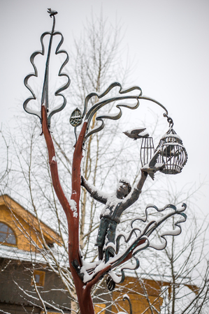 The sculptural composition of metal boy opens the cage and releases birdsの写真素材