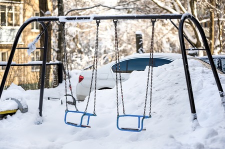 Snow drifts and debris on the playground in one of the cities of Russia in the winterの写真素材