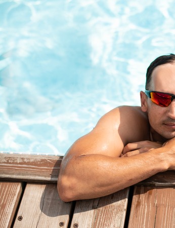 A young handsome brunette man with European features leaned on a wooden pier getting out of the water in the Maldivesの写真素材