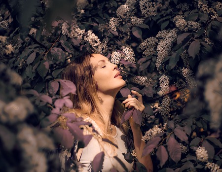macro Portrait of a beautiful girl among red color foliage and flowers bird cherry