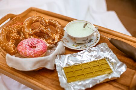 Focus on cappuccinator and antique porcelain cup with whipped cream. green chocolate with the addition of Chinese matcha tea, and pretzels with iced donutsの写真素材