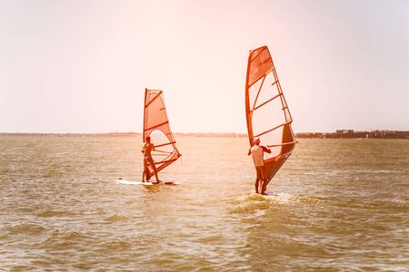 Romance in the sea couple man and woman together sailing on a windsurfing board while on vacation in...
