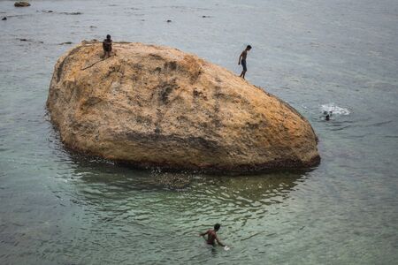 GALLE, SRI LANKA - MARCH 16, 2019: Children boys dive from rocks. Rocks or large stones in the Indian Ocean near Galle Fort in Sri Lankaのeditorial素材
