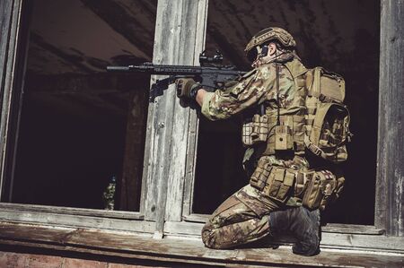 man in military camouflage vegetato uniform with automatic assault rifle storm the old destroyed...