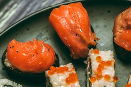 Assorted roll and sushi on a beautiful round plate or tray on a wooden table in a restaurant macro shotの写真素材
