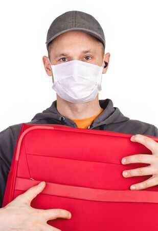 Frightened tourist man in a medical mask presses a red suitcase to himself, the concept cant leave the country, flights canceledの写真素材