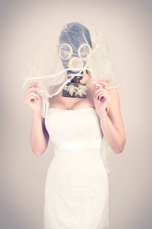 cyberpunk Bride in veil dress and protective mask in a gas mask with rhinestones style posing on a delicate backgroundの写真素材