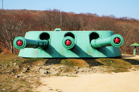 Vladivostok, Russia, 05,11, 2017. Military-historical Museum in the Russian island. Front side of old green russian turret  gun  on the hill with tree barrels and red army stars.のeditorial素材
