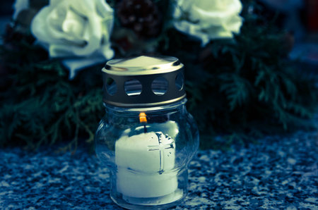 burning candle on grave with wreath