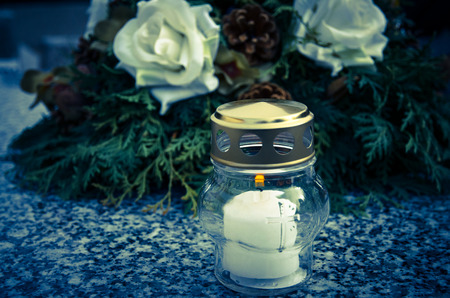 burning candle on grave with wreathの写真素材