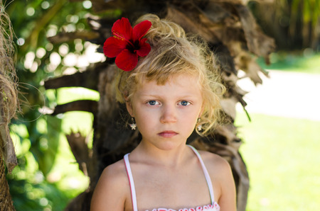 beautiful blond girl with red flowerの写真素材