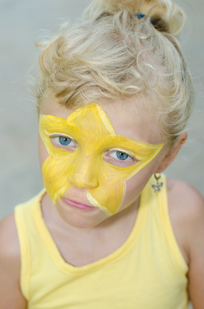 beautiful blond girl with yellow star face paintingの写真素材