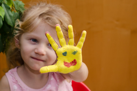 blond girl with painted sun on her handの写真素材