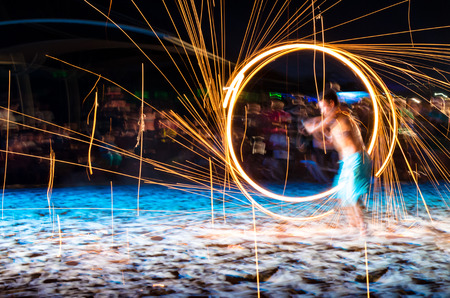 man doing fire show on beach at nightの写真素材
