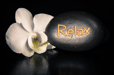 word relax written on lava stone and white orchidの写真素材