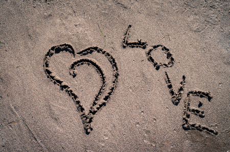 heart drown into sand on beachの写真素材