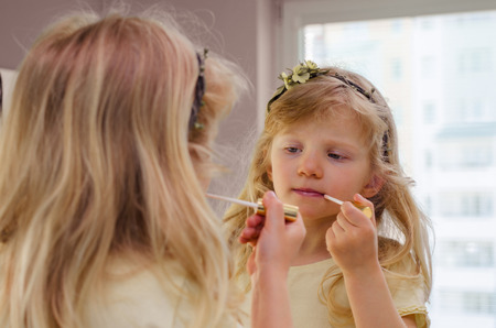 beautiful blond girl painting her lips with lipstickの写真素材