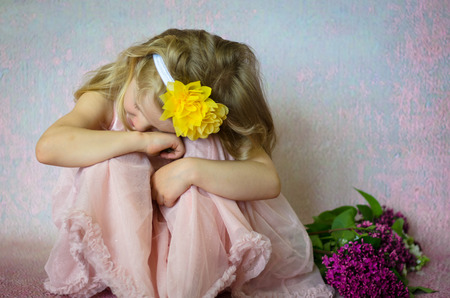 young child girl sitting with flowers, wearing home hand made yellow headbandの写真素材