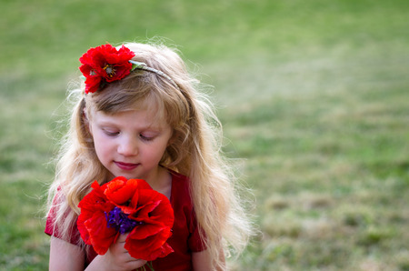 blond girl with long hair and red flowersの写真素材