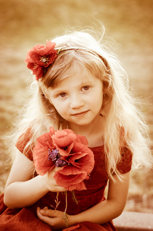blond girl with long hair and red flowers sepia tonedの写真素材