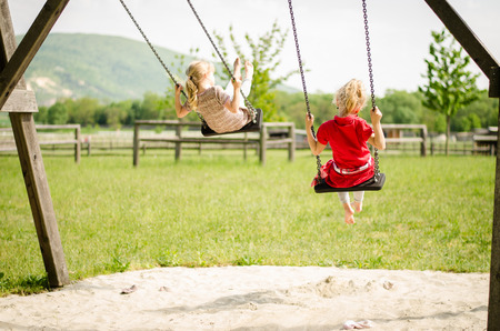 little blond girls swinging outdoorの写真素材