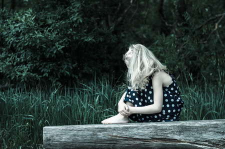 beautiful blond girl sitting on bench and posingの写真素材