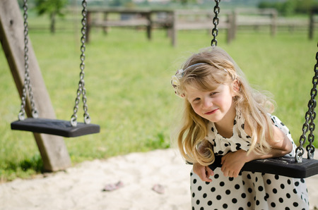 little blond girl swinging outdoorの写真素材
