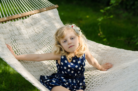 beautiful blond girl lying in white hammockの写真素材