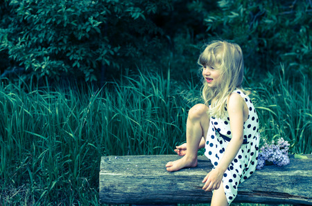 blond girl sitting on benchの写真素材
