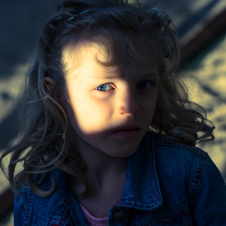 blue eye of blond girl half in shadow