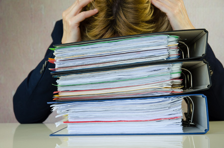 tired businesswoman stressed with pile of folders
