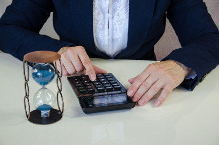 female hand with calculator and sandglassの写真素材