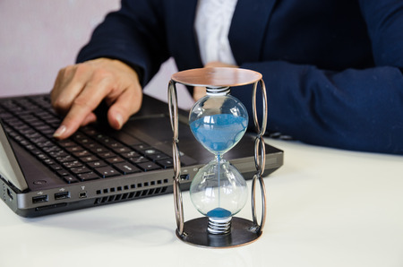 female hand typing in notebook and sandglassの写真素材