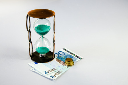 sandglass and eur banknote and coins