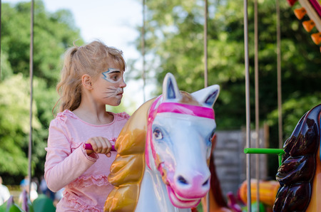 girl with face-painting of cat in marry-go-roundの写真素材