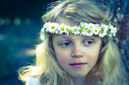 adorable smiling little blond girl with daisy flower headband filtered effectの写真素材