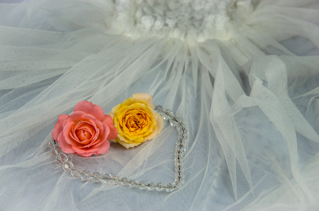 pink and yellow roses over white wedding dressの写真素材
