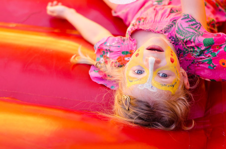 little girl with bright colorful facepaintingの写真素材