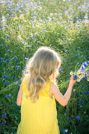 adorable blond girl in yellow dress  back viewの写真素材