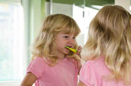 beautiful blond girl with long hair brushing her teethの写真素材
