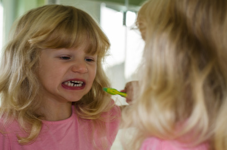 beautiful blond girl with long hair brushing her teeth