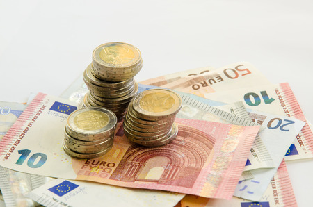 euro banknotes with different denomination and pile of coinsの写真素材