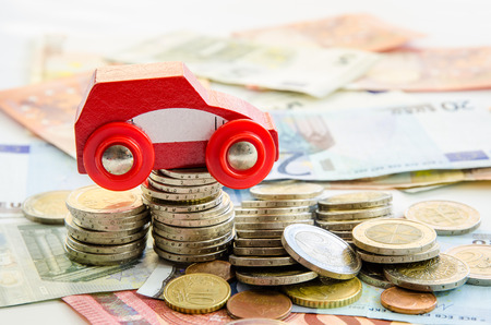 red toy car on banknotes and coinsの写真素材