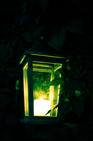burning candle in the wooden lantern
